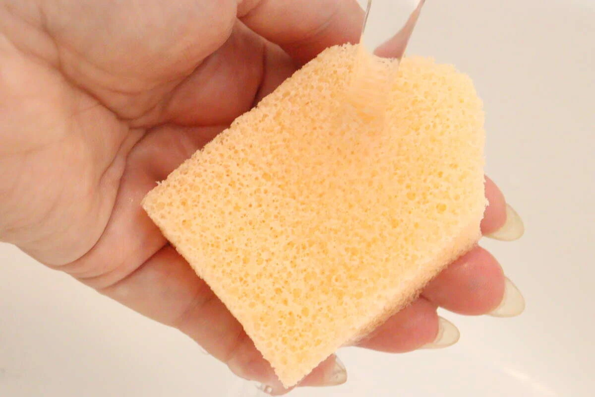 手に持ったハウス型洗顔パフに蛇口から水をかけている