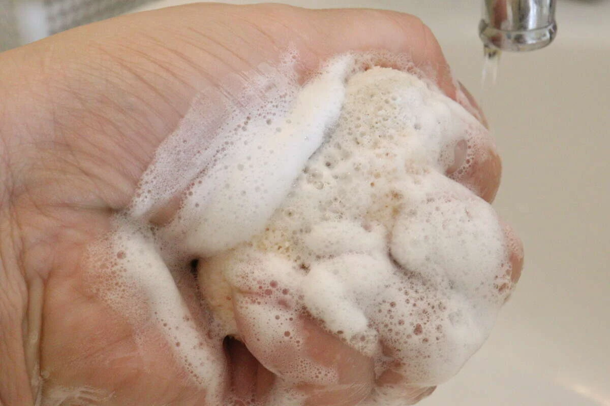 洗顔料をつけたひょうたん型の洗顔パフを手のひらで揉み泡立てている 洗顔料をつけたひょうたん型の洗顔パフを手のひらで揉み泡立てている