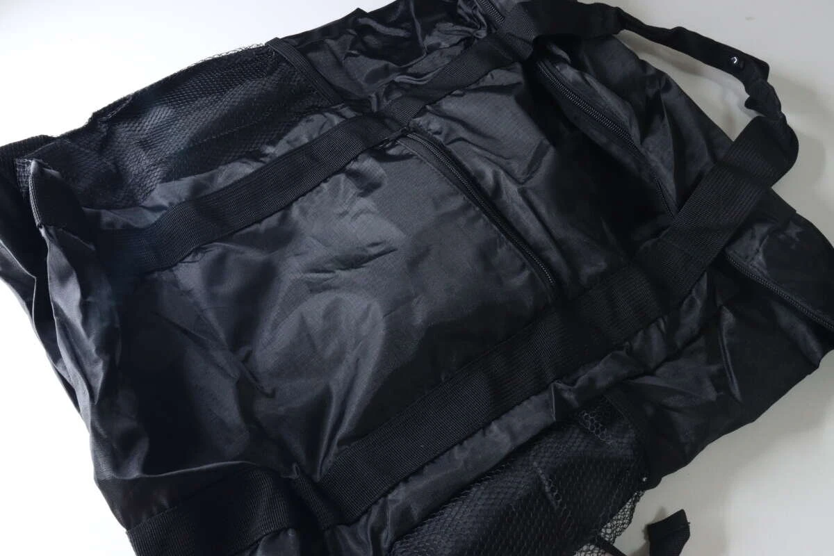 黒いトート型バックパックが広げられた状態。メッシュポケットやファスナー付きポケットが見える。