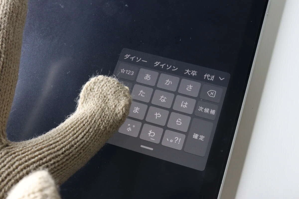 手袋を着用した指でタブレットのキーボードを操作している