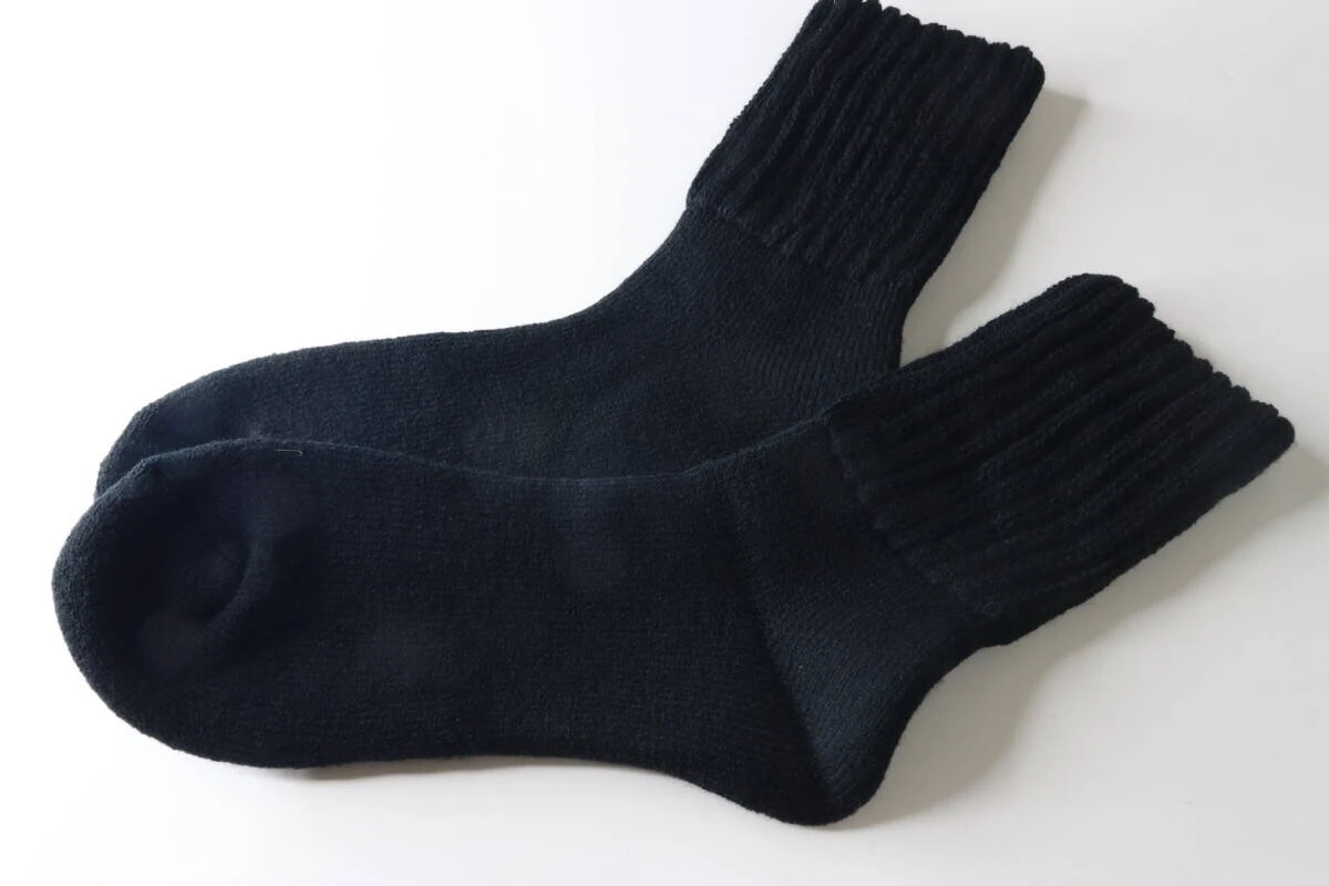 白い背景に並べられた黒い裏起毛パイルソックス2足。 白い背景に並べられた黒い裏起毛パイルソックス2足。