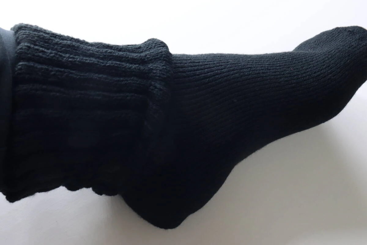 黒いゆったりソックスを履いた足の側面。足首に締め付けがない様子。 黒いゆったりソックスを履いた足の側面。足首に締め付けがない様子。