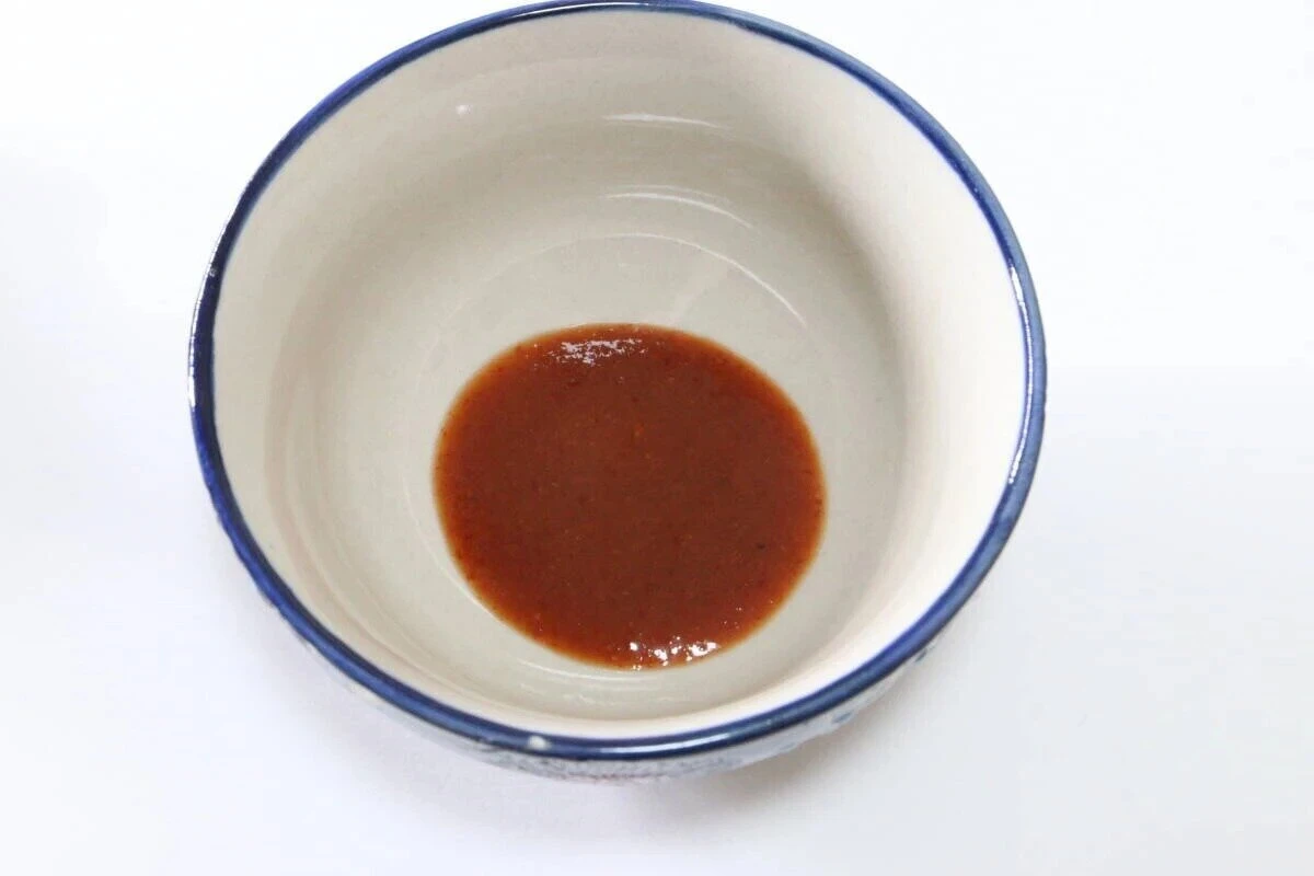 白いお椀の底に赤茶色のスリラチャソースが少量入っている 白いお椀の底に赤茶色のスリラチャソースが少量入っている
