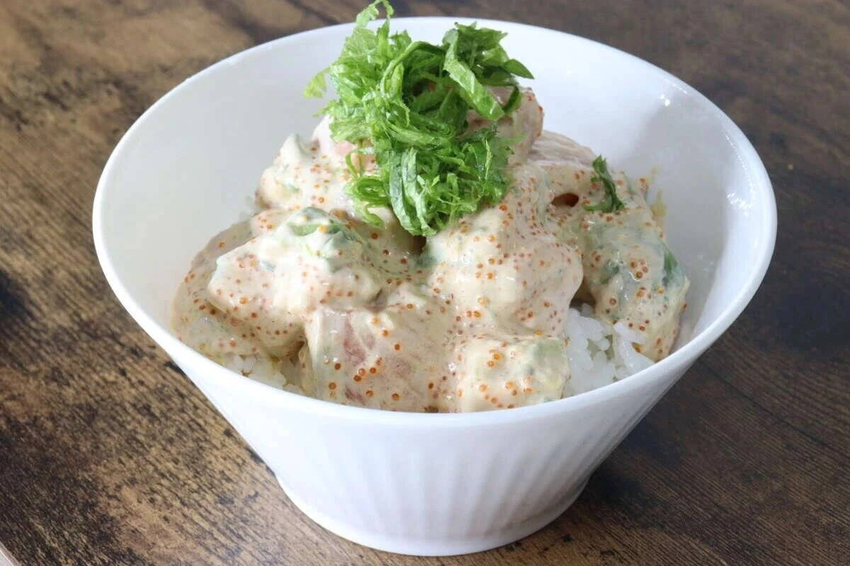 白い丼ぶりに盛られたサーモンサラダ丼。刻みネギが乗っている 白い丼ぶりに盛られたサーモンサラダ丼。刻みネギが乗っている