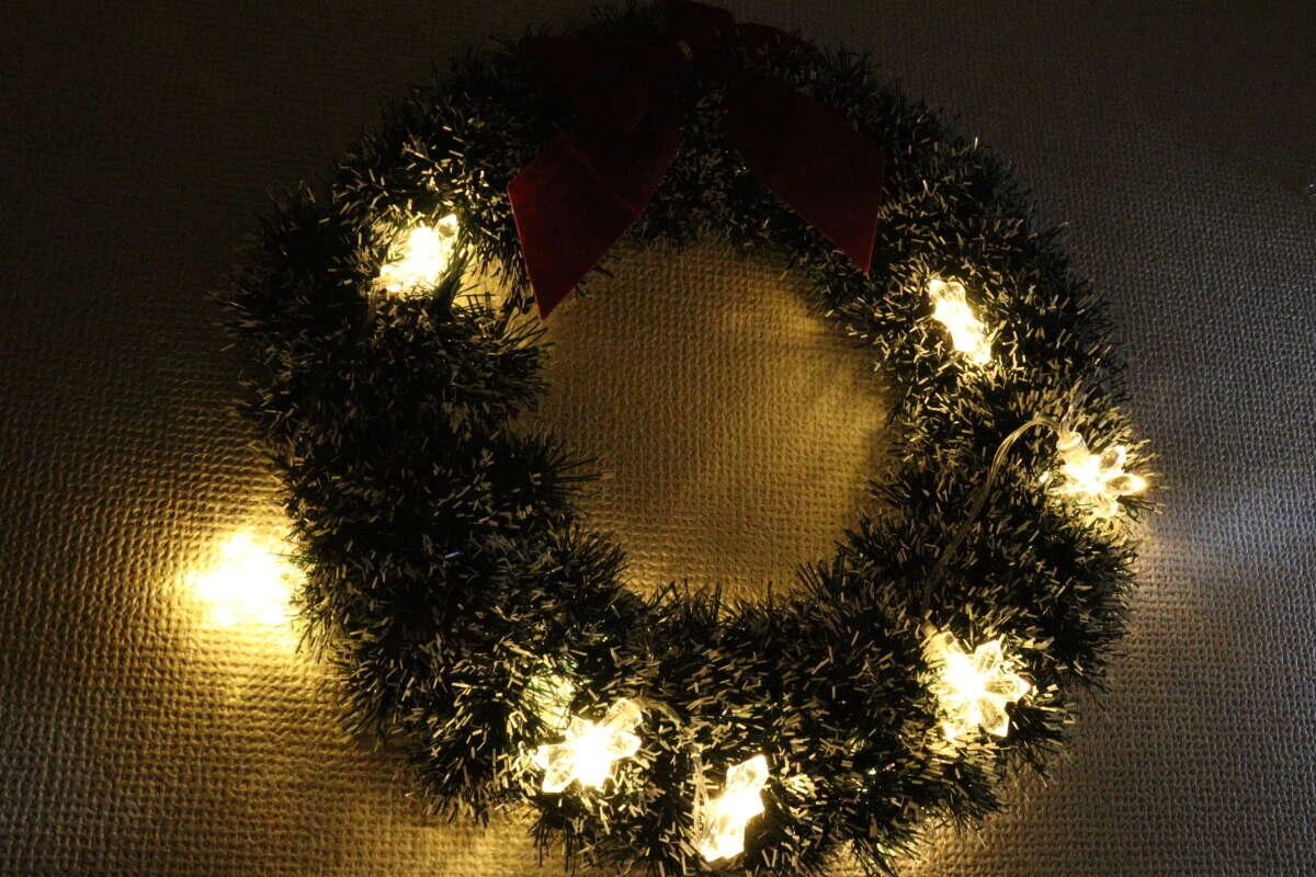 クリスマスリースに飾られた雪の結晶ライトが点灯している クリスマスリースに飾られた雪の結晶ライトが点灯している