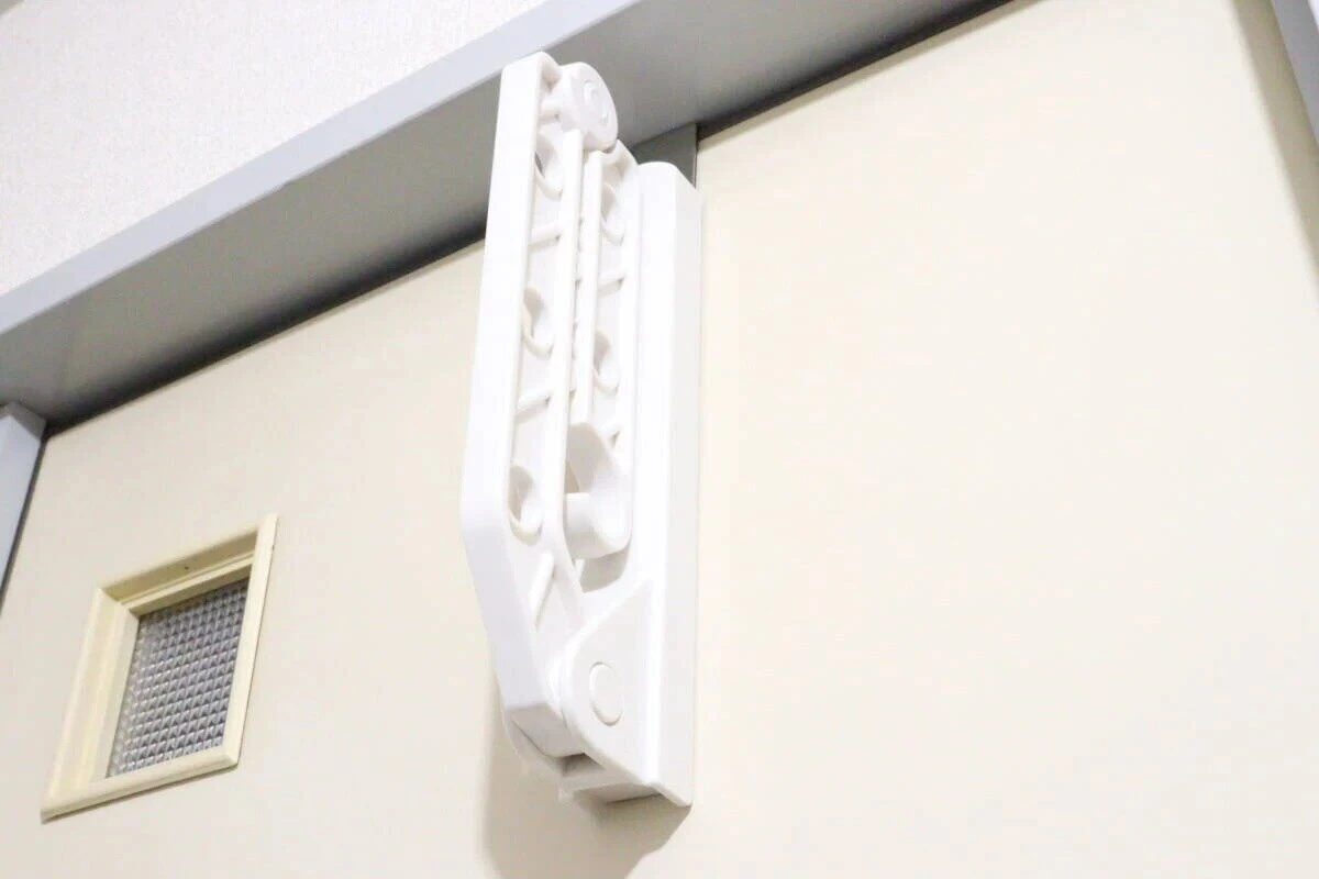 ドアに引っ掛けられてコンパクトに折り畳まれている白い物干しラック ドアに引っ掛けられてコンパクトに折り畳まれている白い物干しラック