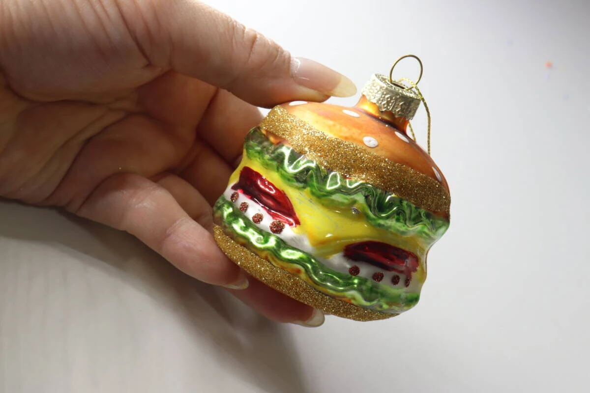 手のひらに乗せられたボリューム感のあるハンバーガーモチーフのガラスオーナメント