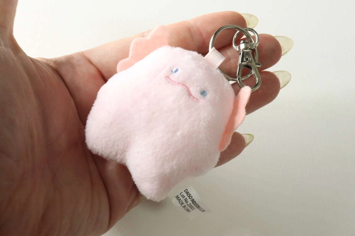 女性の手のひらに乗せられた手のひらサイズのピンク色のマスコット