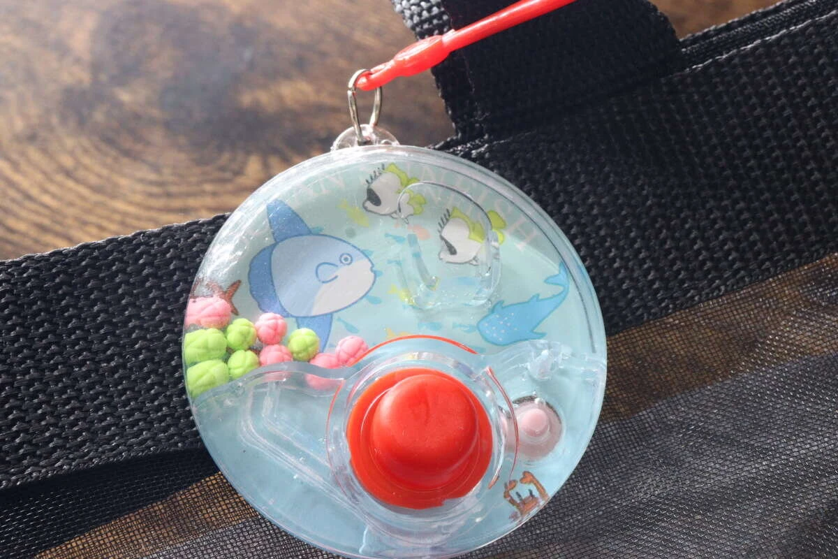 黒いバッグの持ち手にキーホルダーで取り付けられたゲーム機 黒いバッグの持ち手にキーホルダーで取り付けられたゲーム機