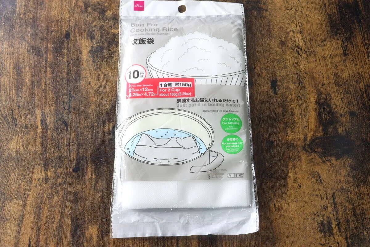木目のテーブルの上に置かれたダイソーの炊飯袋のパッケージ表面 木目のテーブルの上に置かれたダイソーの炊飯袋のパッケージ表面