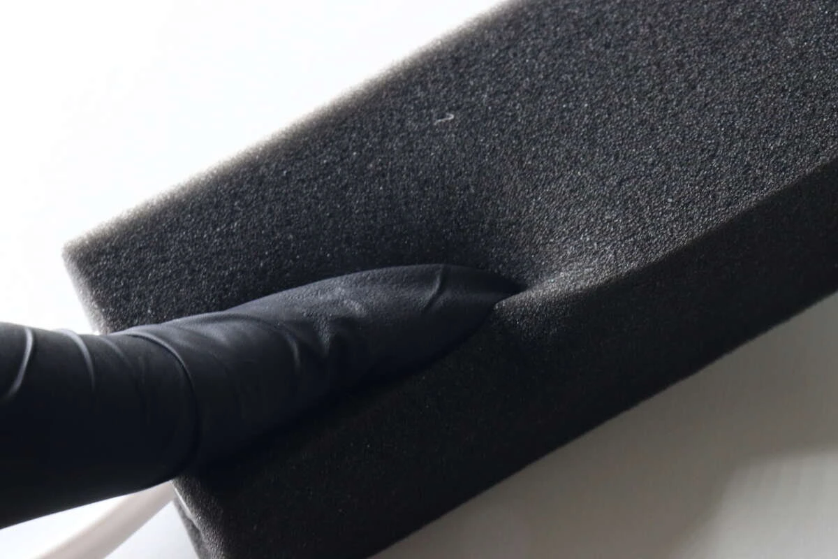黒い手袋をした指でやわらかなスポンジの素材感を確認している様子 黒い手袋をした指でやわらかなスポンジの素材感を確認している様子