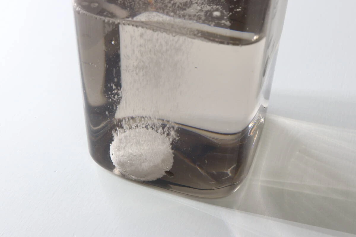 茶色い容器の水の中で錠剤が発泡しながら溶けていく瞬間 茶色い容器の水の中で錠剤が発泡しながら溶けていく瞬間