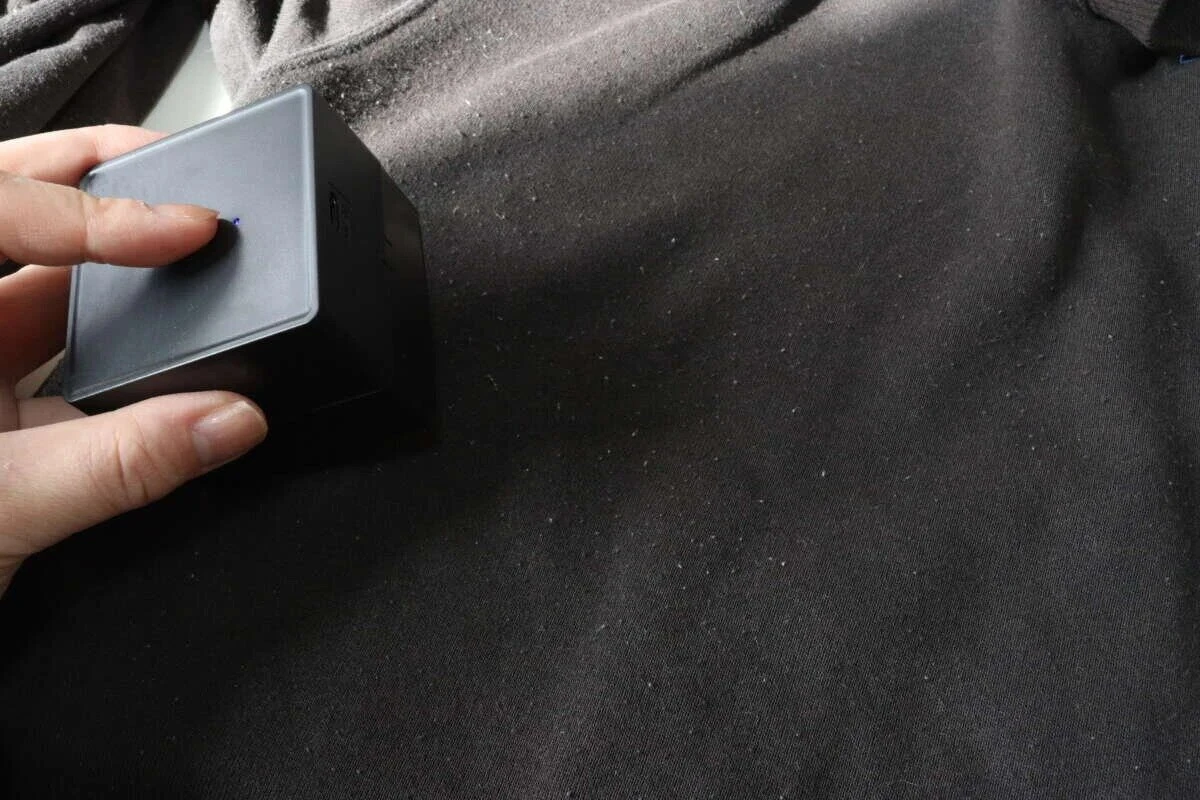 黒い衣類の上に電動毛玉取りを当てて電源ボタンを押している様子