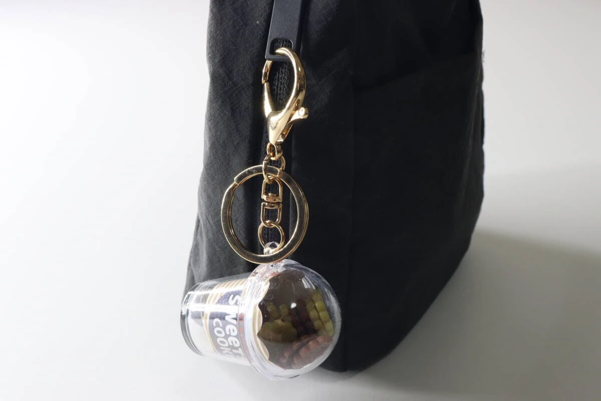 黒いバッグの持ち手にゴールドの金具で取り付けられたキーホルダー