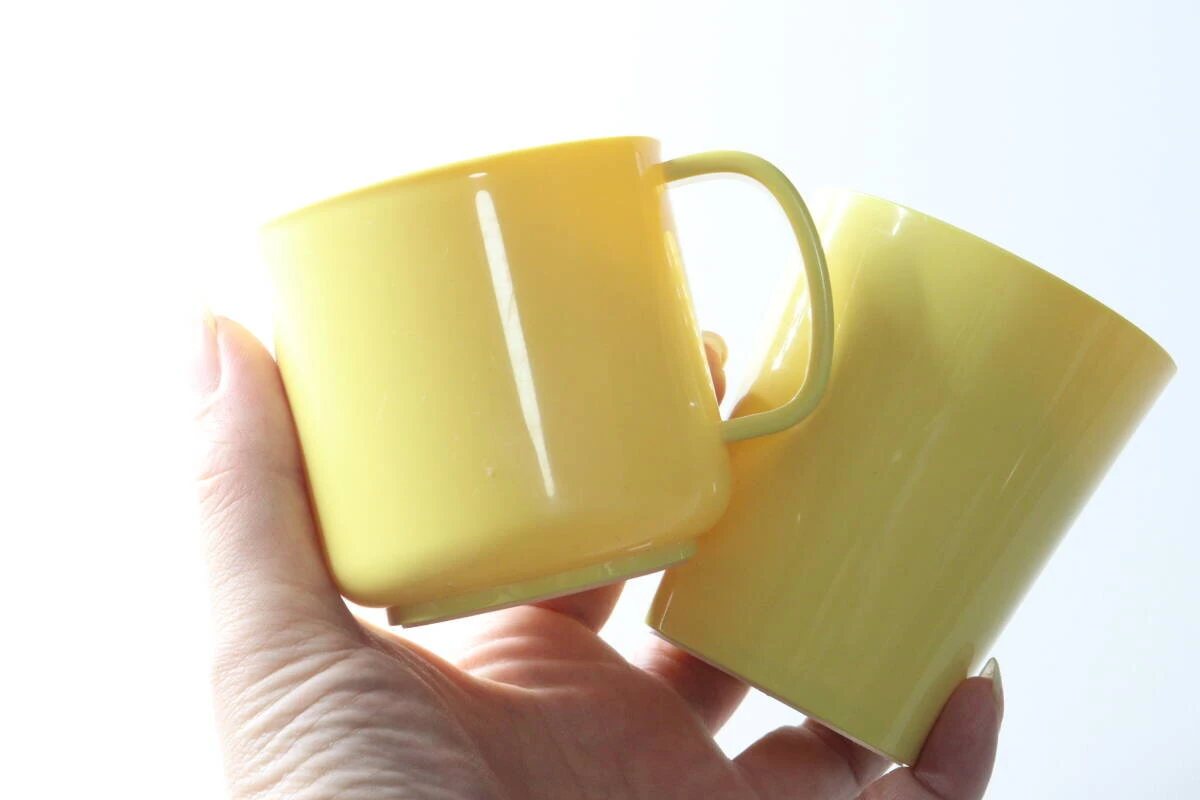 手のひらに黄色いマグカップとカップを乗せている状態 手のひらに黄色いマグカップとカップを乗せている状態