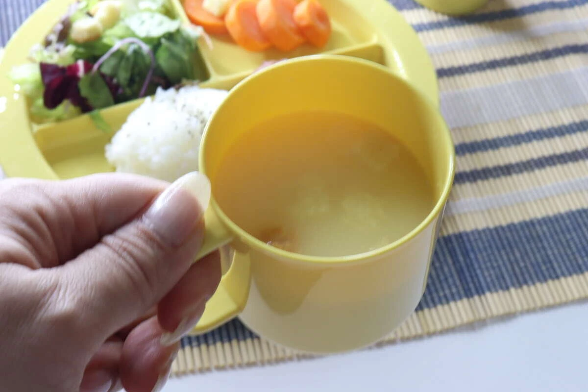 スープが入ったマグカップを持ち上げて見せている様子 スープが入ったマグカップを持ち上げて見せている様子