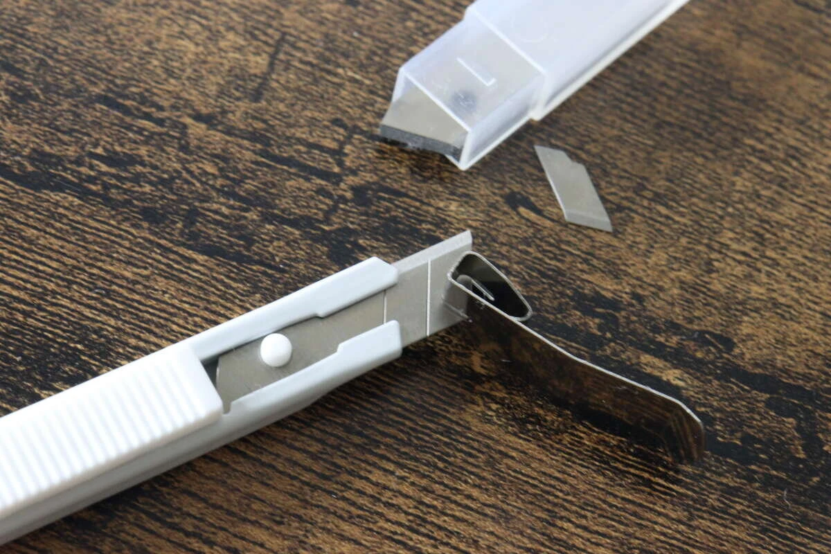 上部の金属製刃折器を使ってカッターの刃を折っている様子