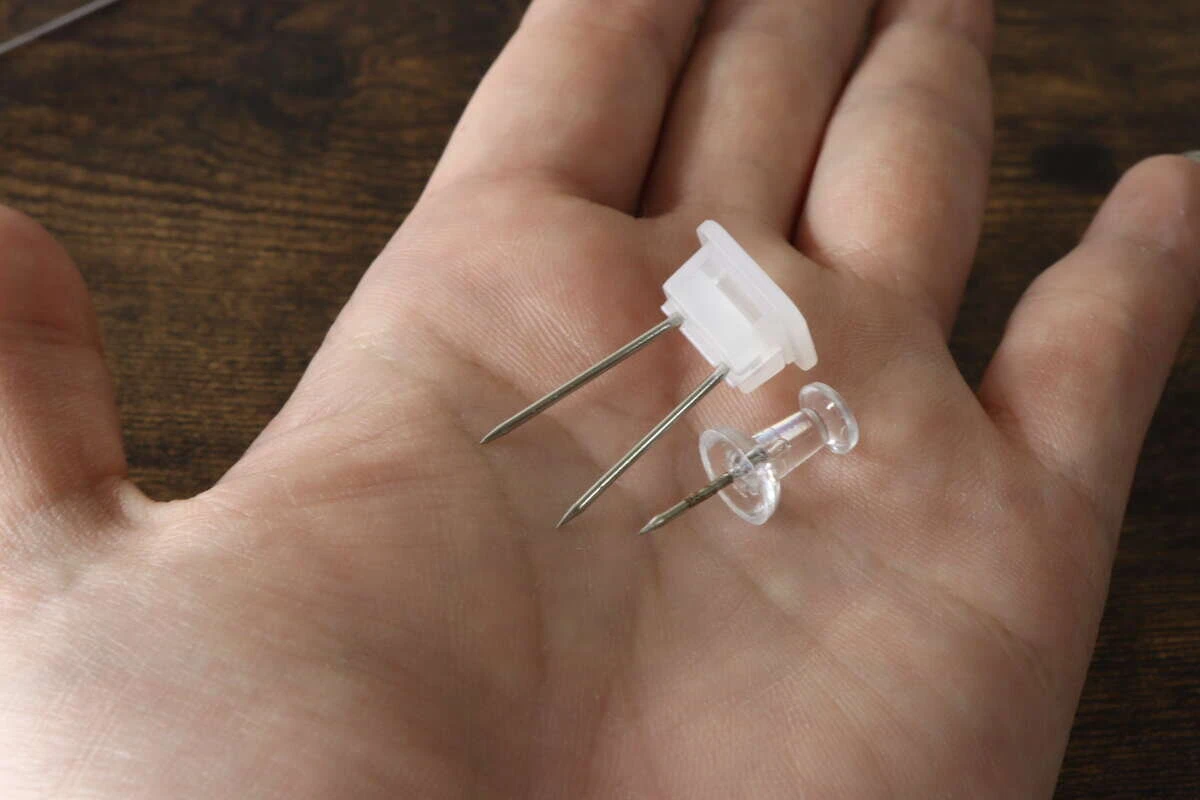 手の平の上に専用の長めのピンと通常のプッシュピンを並べて比較している様子