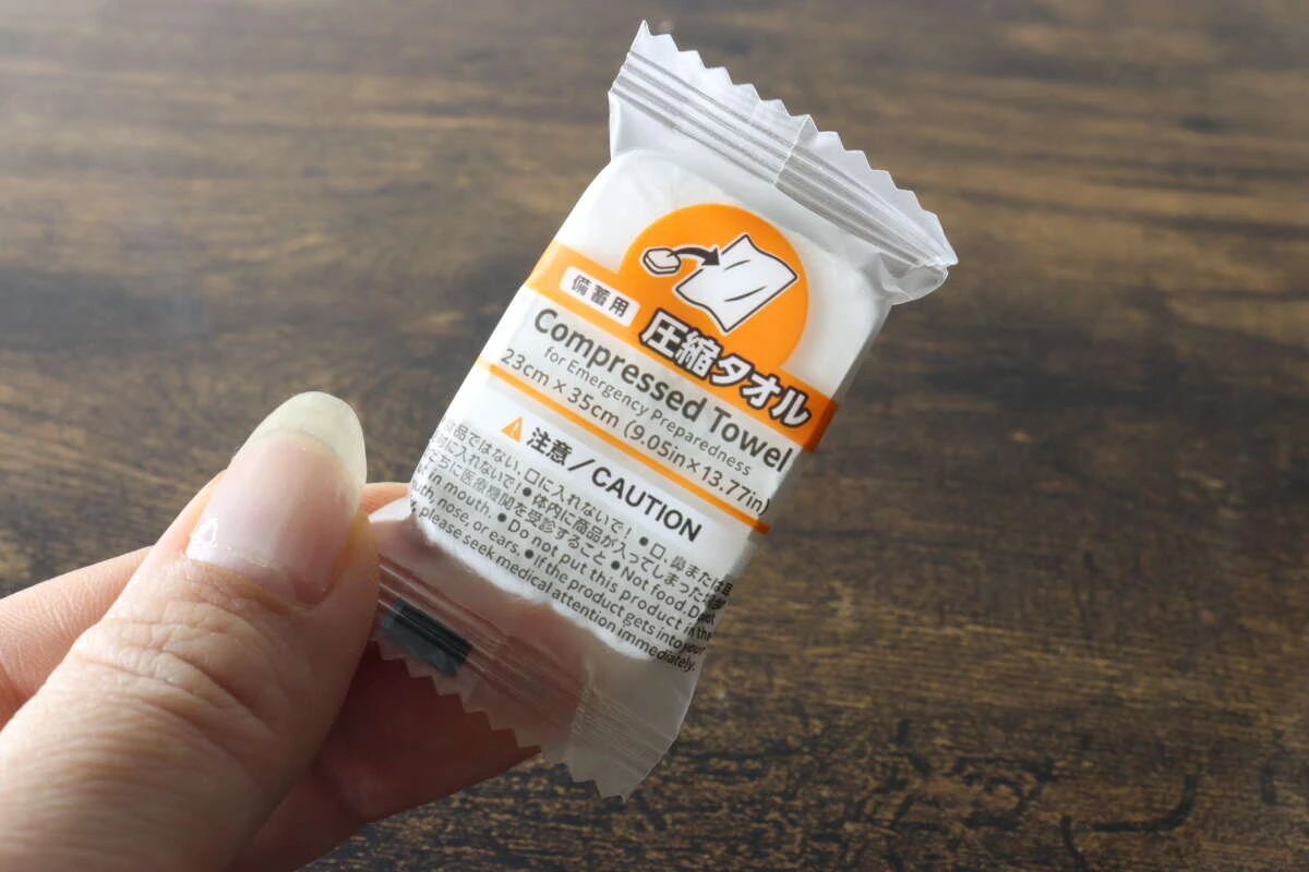 個包装された小さな圧縮タオルを1個手に持って見せている状態 個包装された小さな圧縮タオルを1個手に持って見せている状態