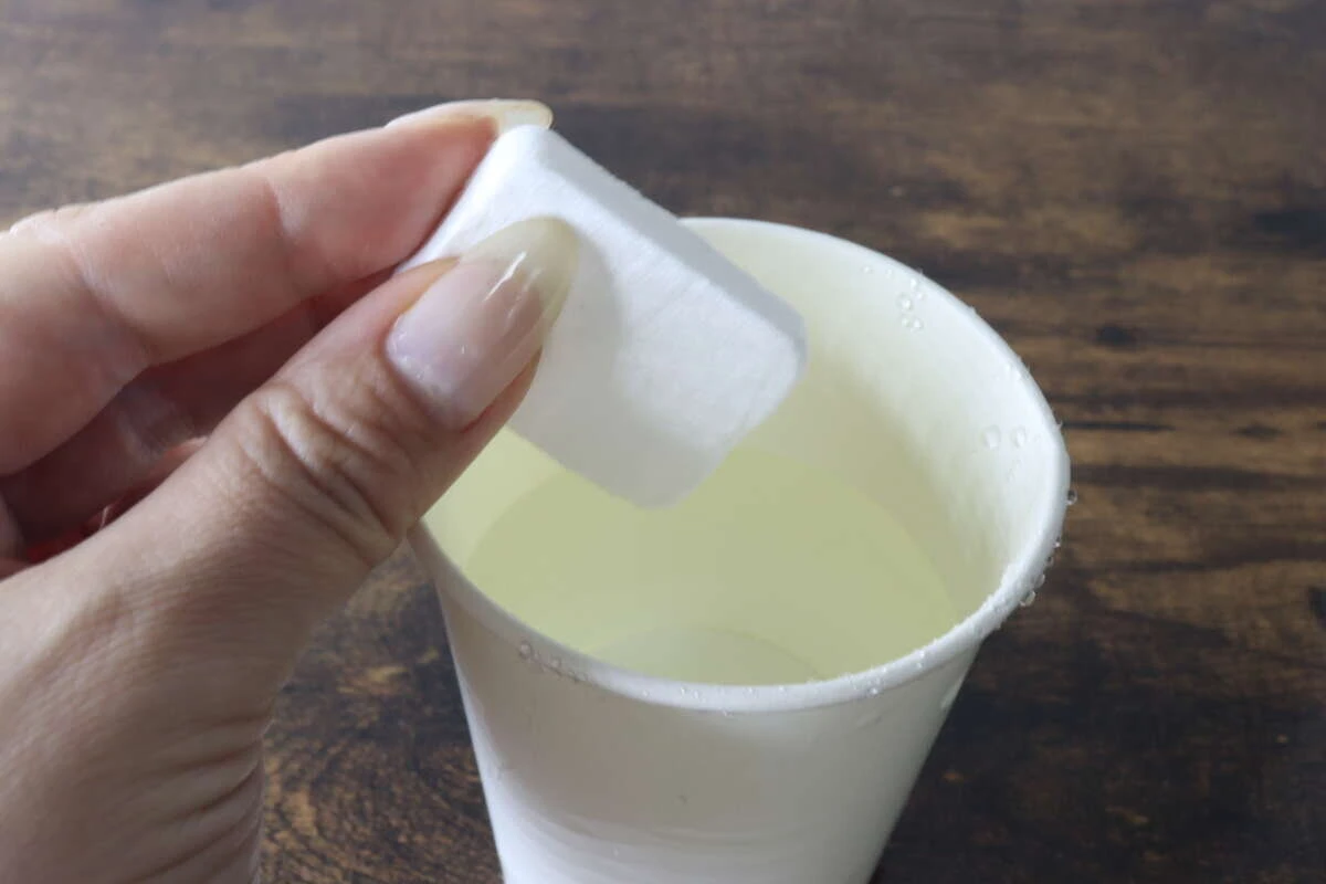 水を入れた紙コップに圧縮タオルを浸そうとしている瞬間 水を入れた紙コップに圧縮タオルを浸そうとしている瞬間