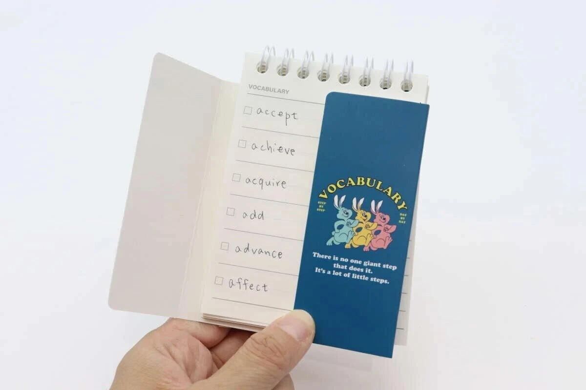 単語帳の表紙の片側をめくって右側の意味部分を隠している様子を示す手元写真