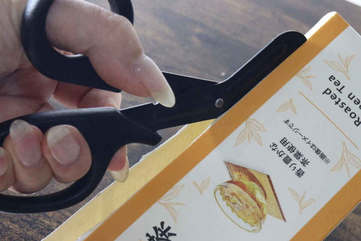 ギザ刃を備えたキッチンハサミで紙パックの側面をスムーズに切っている状態