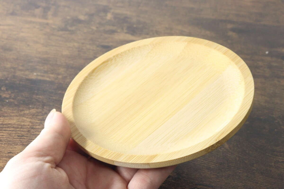 手に持ってサイズ感を示している丸形のバンブートレー 手に持ってサイズ感を示している丸形のバンブートレー