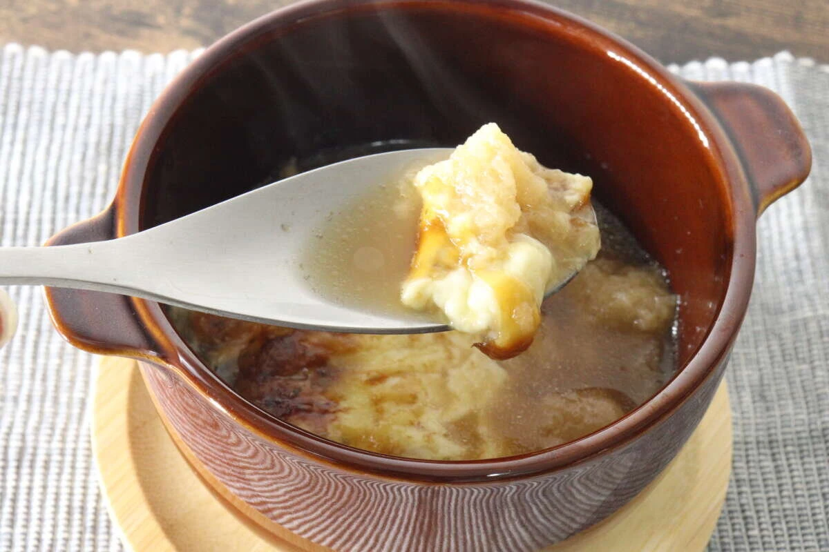 スープボウルからスプーンでとろけたチーズをすくい上げている様子 スープボウルからスプーンでとろけたチーズをすくい上げている様子