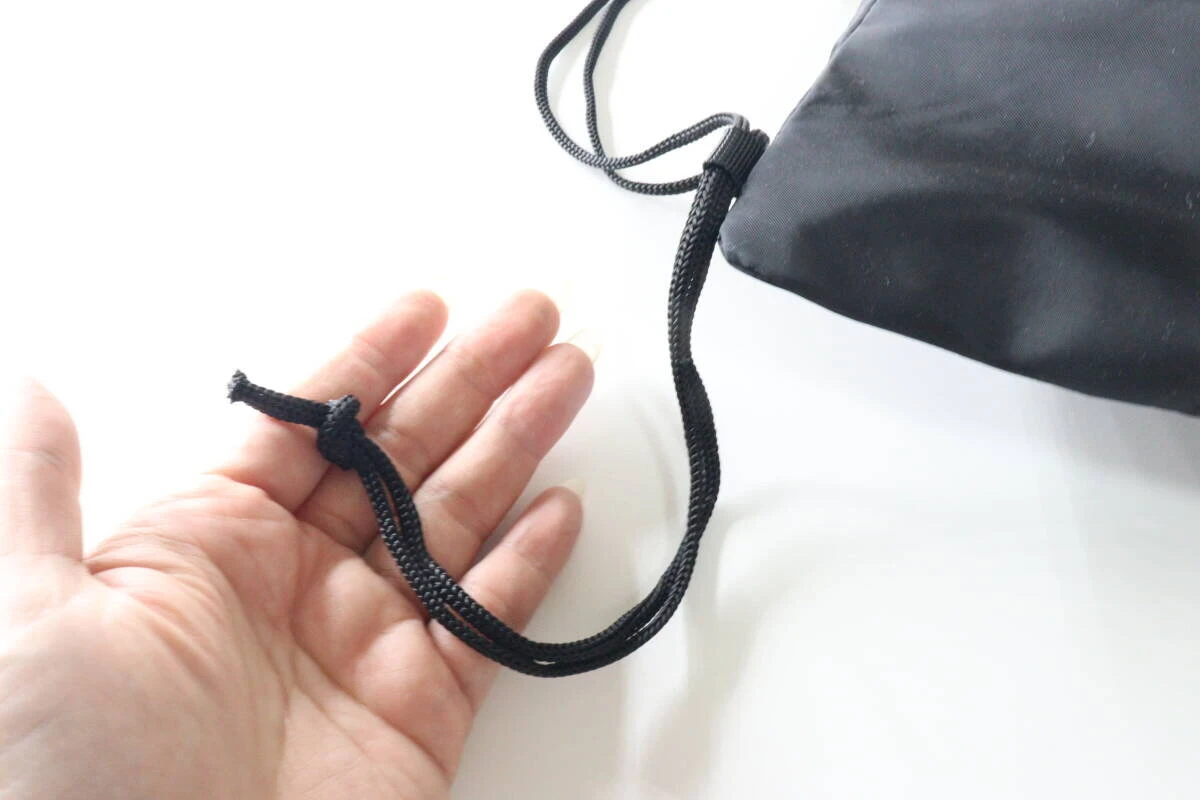 長めのショルダー紐を結んで長さ調節をしている手のひらと紐の様子