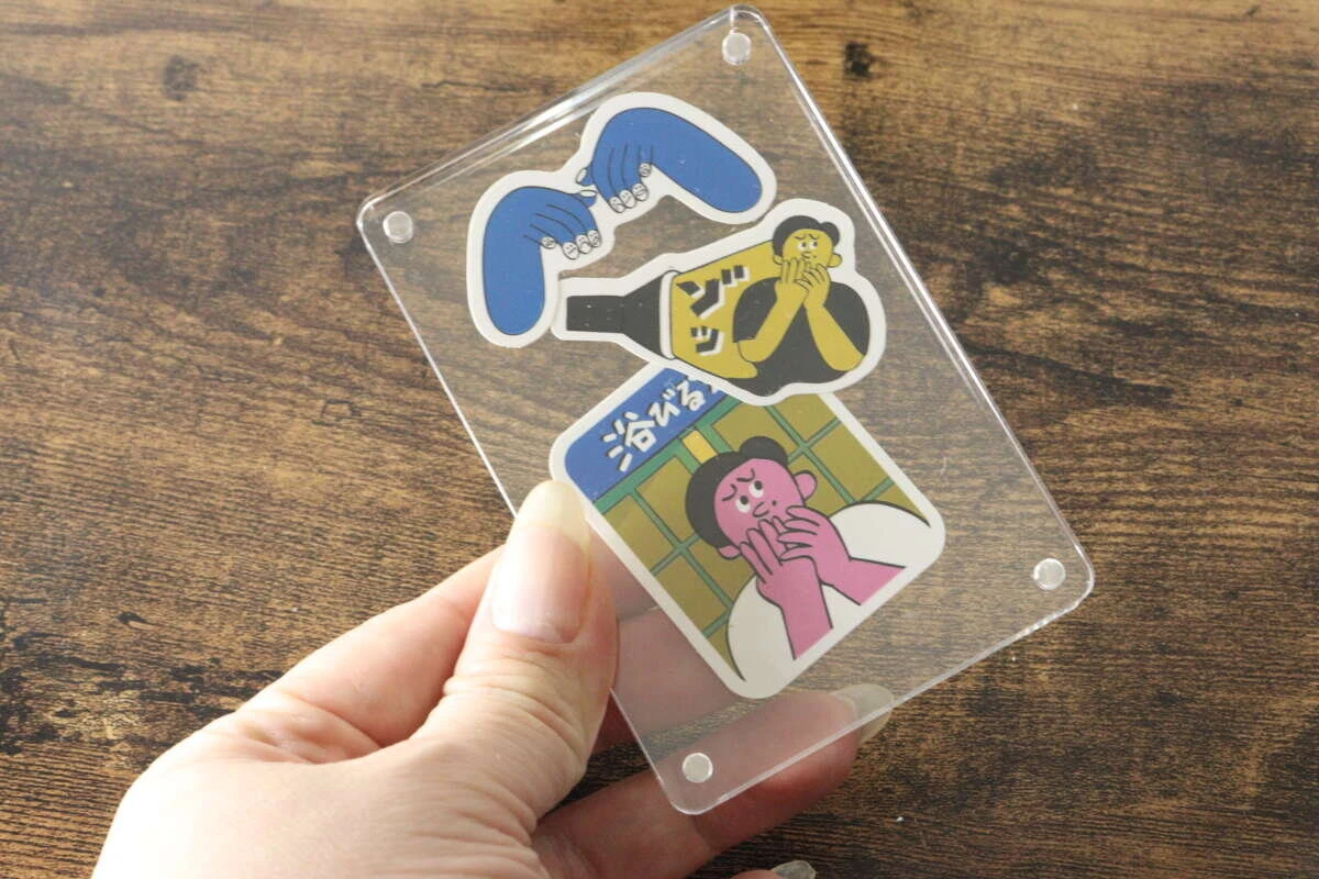 ステッカーを挟んだアクリルフレームを手で持って見せているところ