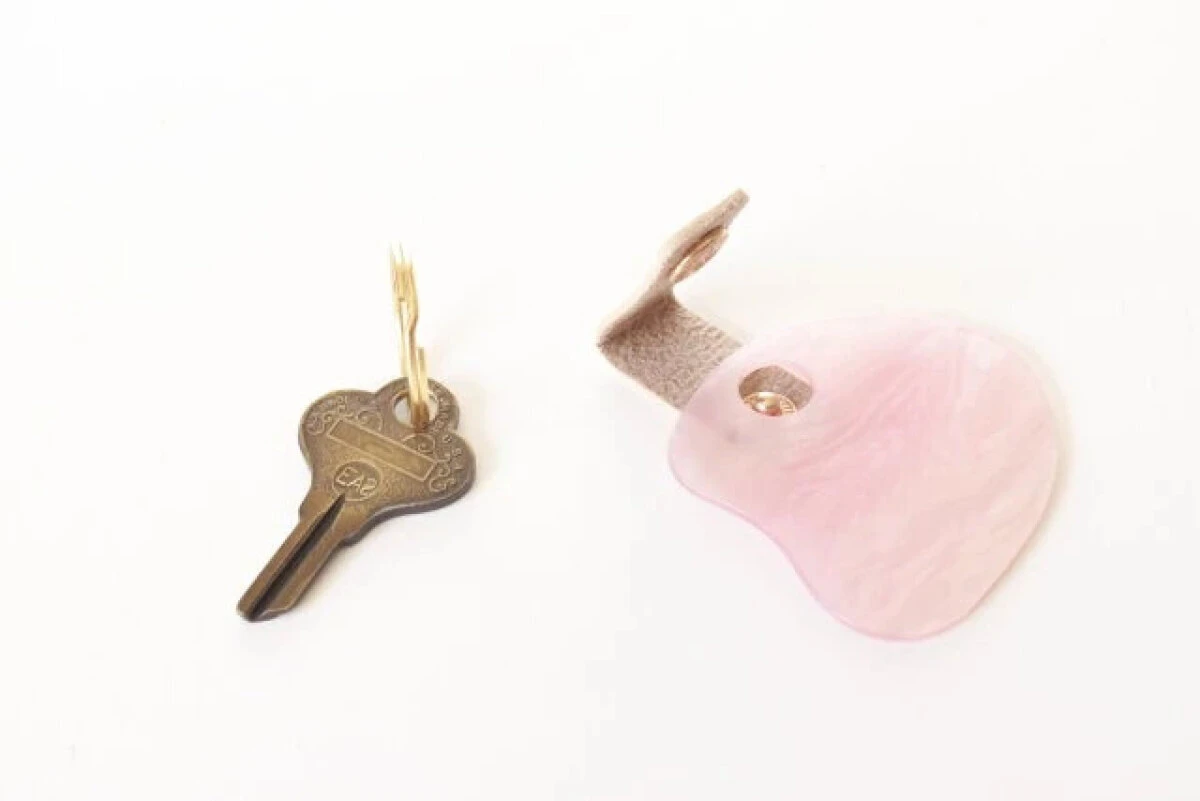 鍵と、ボタンが外れて分離した状態のピンク色のシェル風アクリルキーホルダー 鍵と、ボタンが外れて分離した状態のピンク色のシェル風アクリルキーホルダー