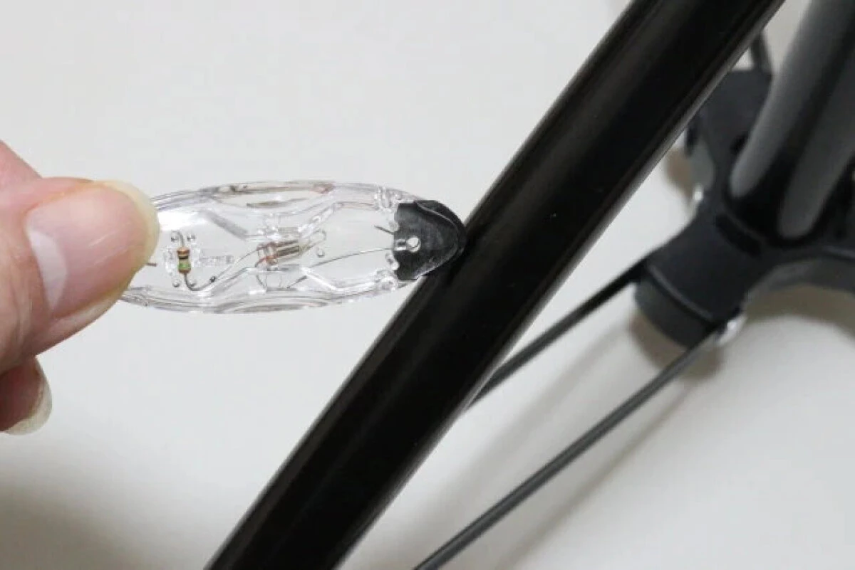 指で持った静電気除去キーホルダーを、金属製の棒に近づけている様子 指で持った静電気除去キーホルダーを、金属製の棒に近づけている様子