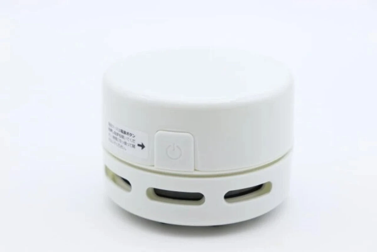 白い背景に置かれた電源ボタンが見える白い円形の卓上クリーナー