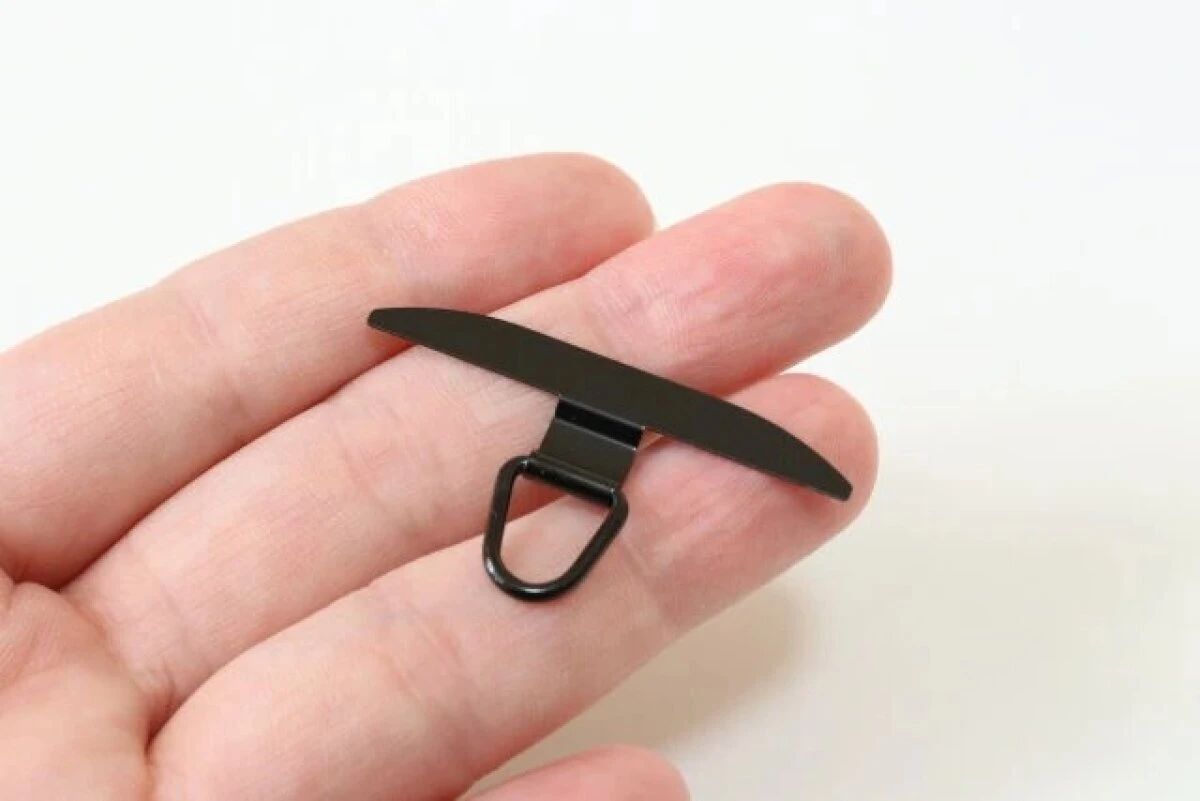 指の上に黒いステンレス製のスマホストラップホルダーを乗せている状態 指の上に黒いステンレス製のスマホストラップホルダーを乗せている状態