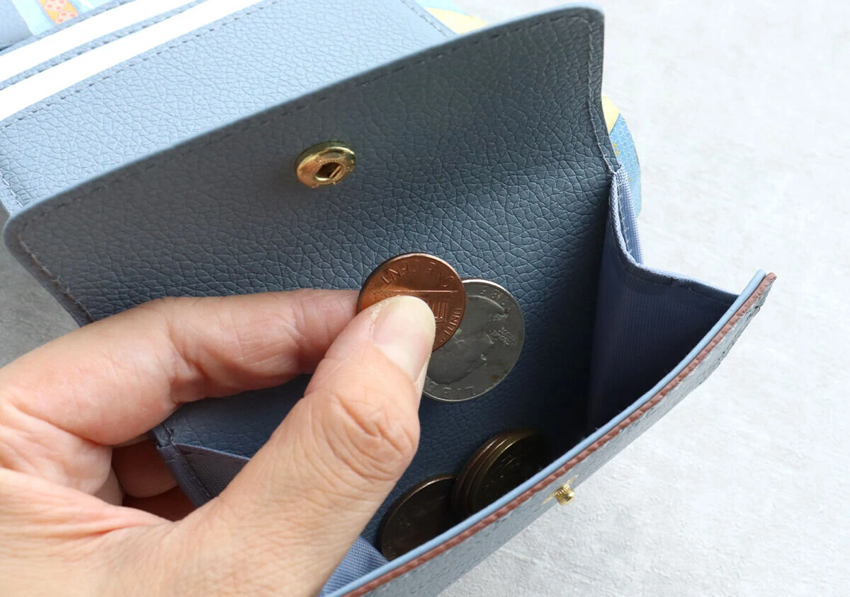 ミニ財布の小銭入れから指でコインを取り出している様子 ミニ財布の小銭入れから指でコインを取り出している様子