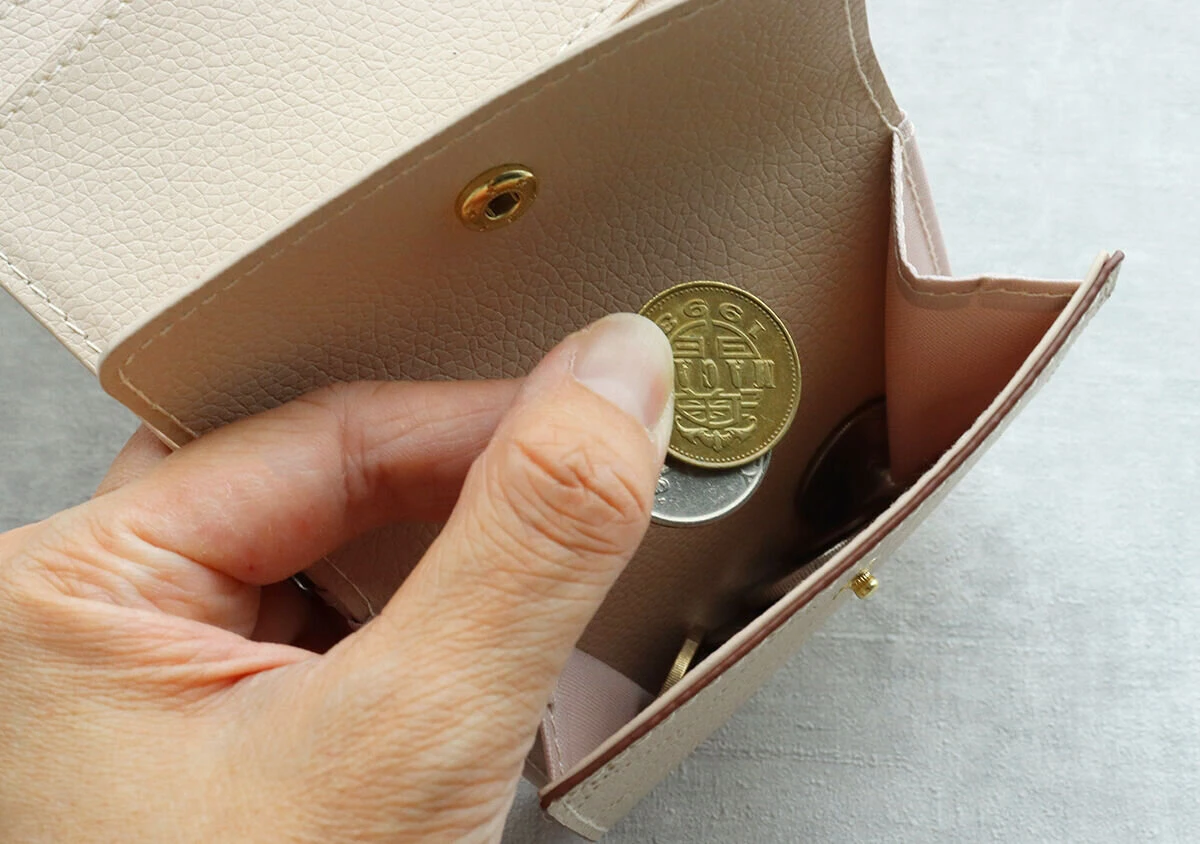 ミニ財布の小銭入れから10円玉を取り出そうとしている手のアップ ミニ財布の小銭入れから10円玉を取り出そうとしている手のアップ