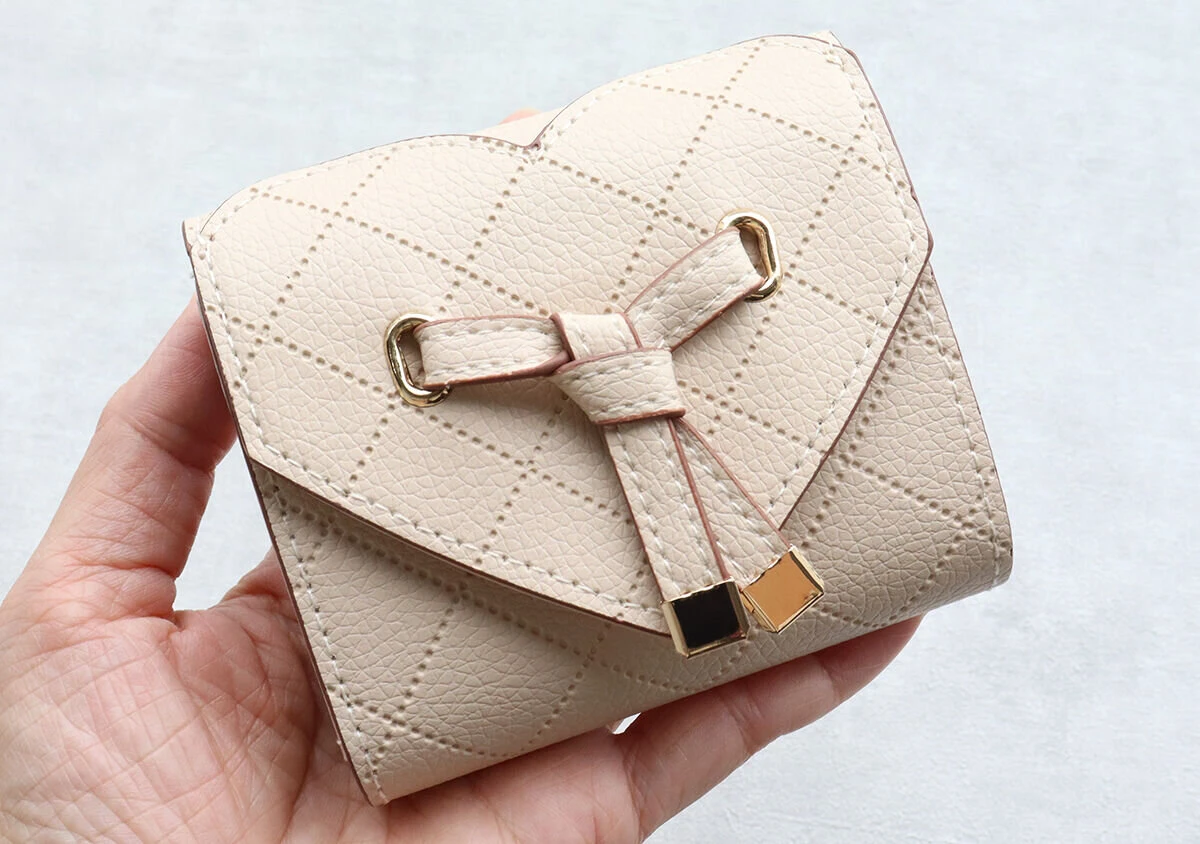 手のひらに乗せられたベージュのVISハートカットミニ財布 手のひらに乗せられたベージュのVISハートカットミニ財布