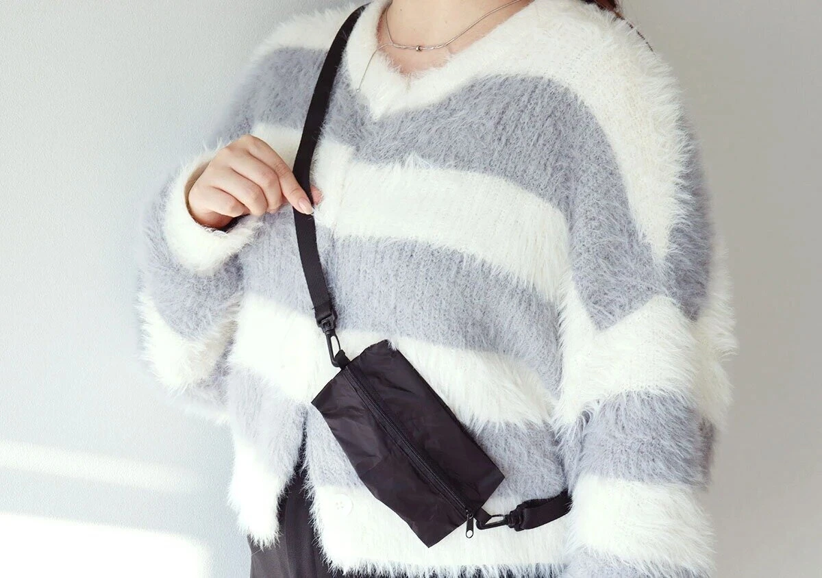 ボーダー柄のセーターを着た女性が黒い折りたたみ式ボディバッグを斜め掛けしている