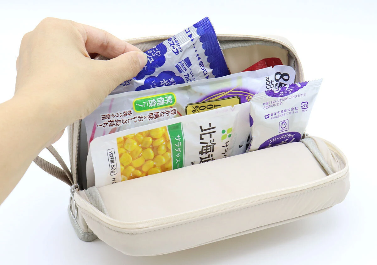 女性の指が、ポーチに収納されたレトルト食品を取り出そうとしている 女性の指が、ポーチに収納されたレトルト食品を取り出そうとしている