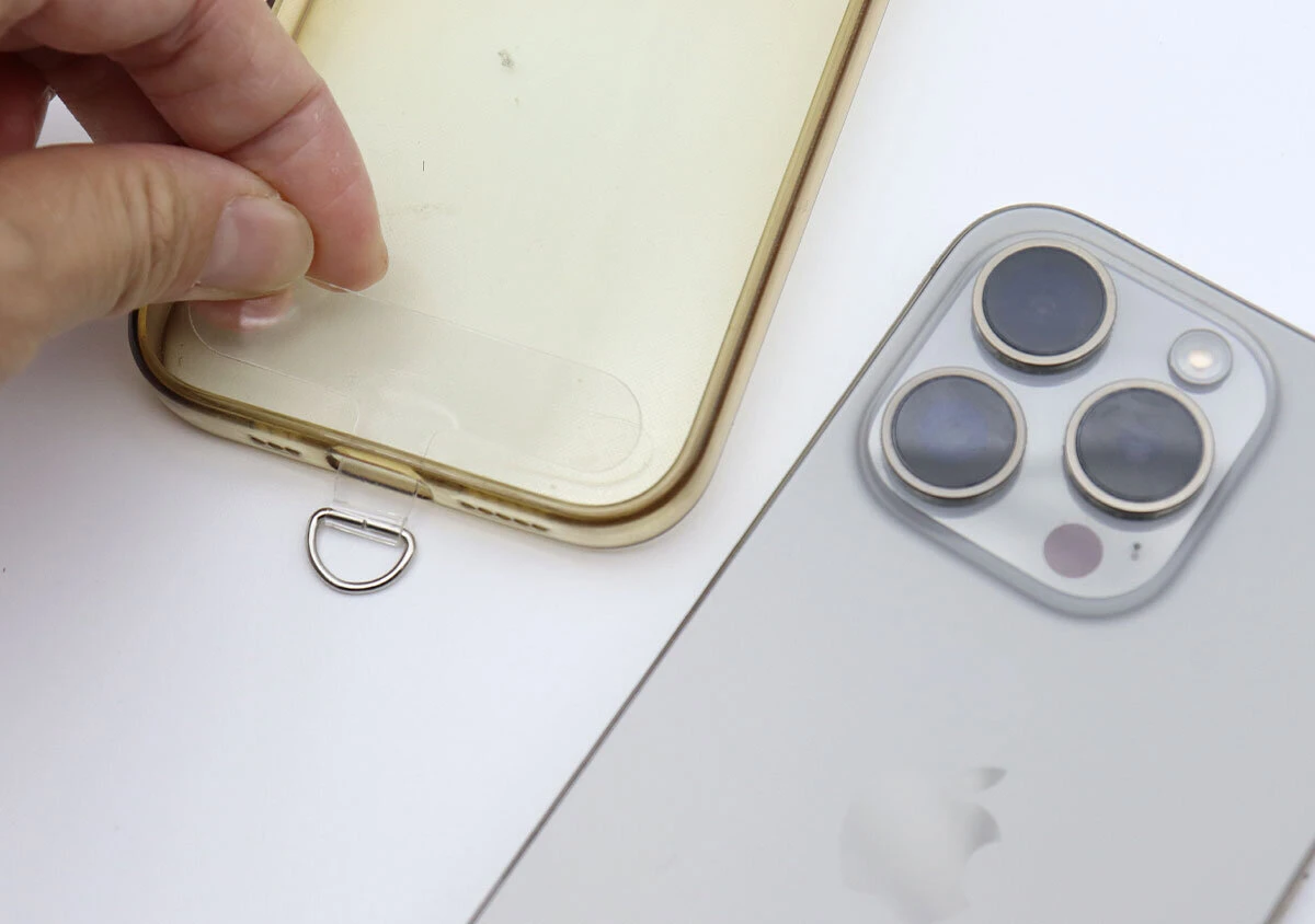 スマートフォンのクリアケースの充電口に透明なアタッチメントを挟み込んでいる手元