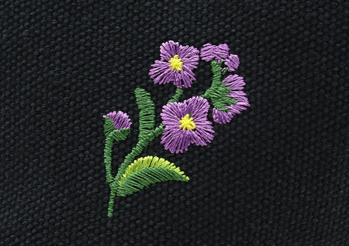紫色の花と緑の葉が細かく丁寧に刺繍されているアップ写真