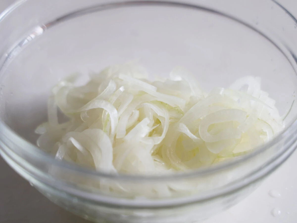 薄切りにした玉ねぎがガラスボウルに入っている 薄切りにした玉ねぎがガラスボウルに入っている