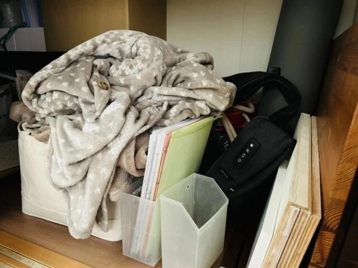 クローゼットの棚に、毛布や書類、バッグなどが雑然と積み重ねられている