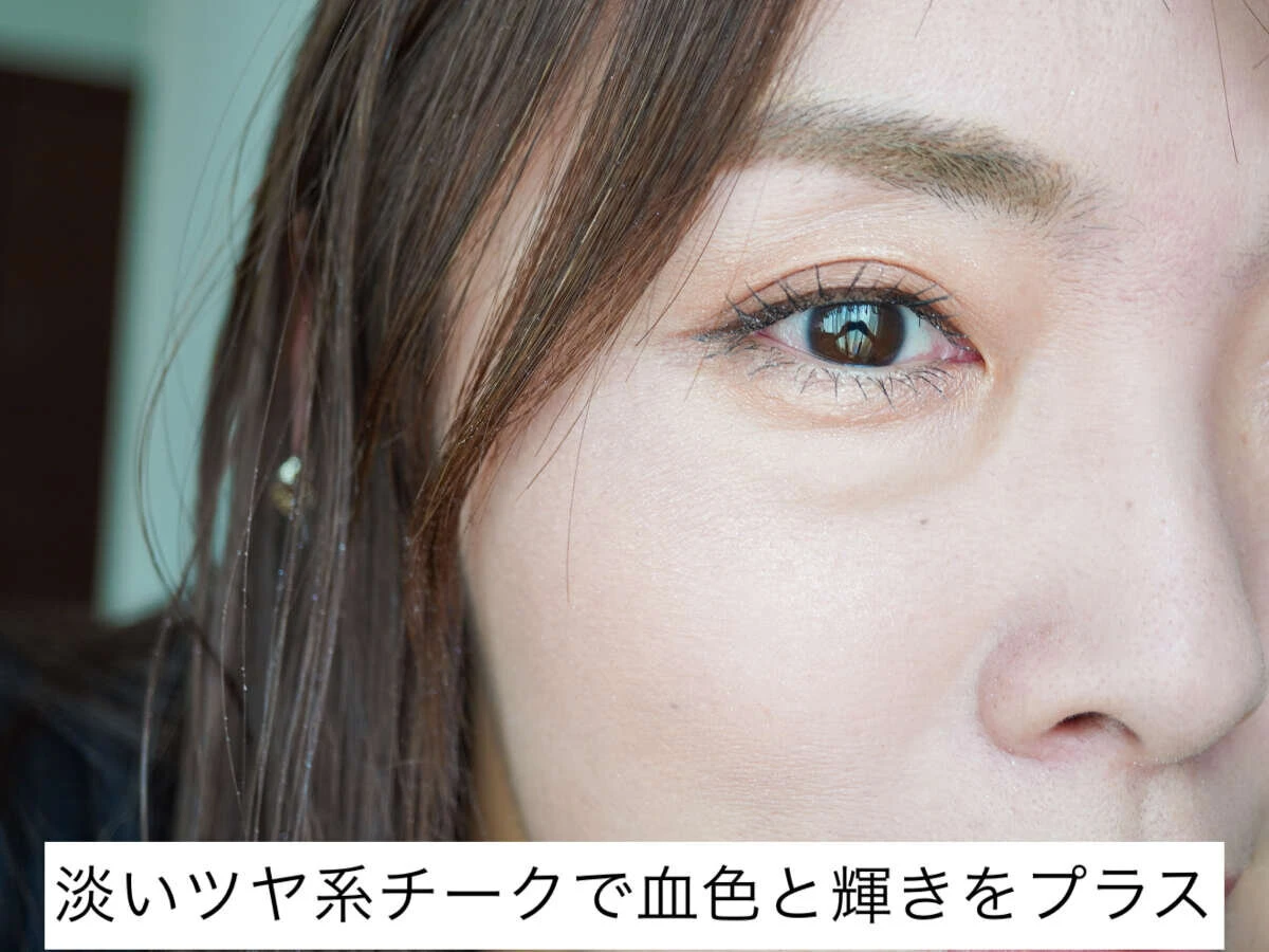 40代女性が目の下に淡いツヤ系チークを塗布し血色をプラスしている。