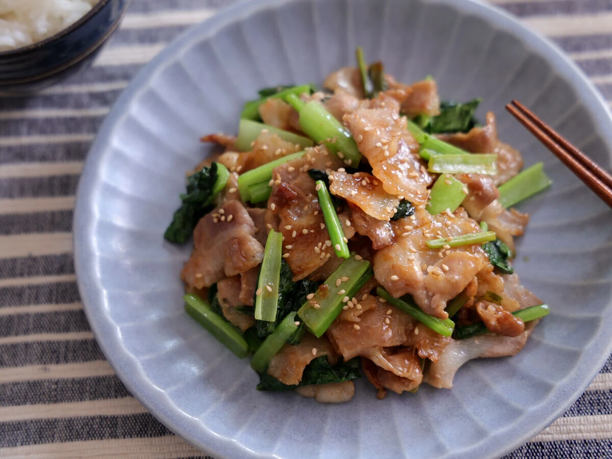 グレーの皿に盛られた豚バラと小松菜のめんつゆ炒め