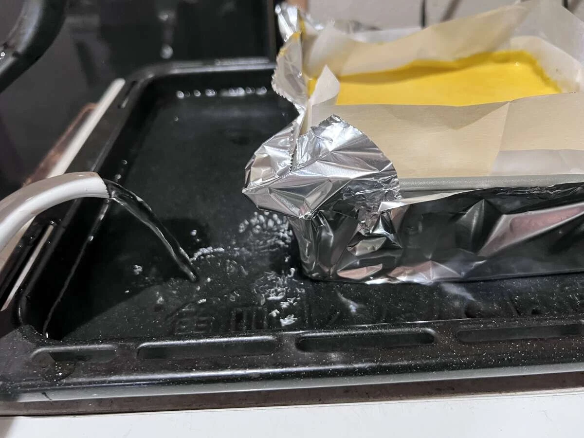 アルミホイルで覆ったスクエア型を天板に乗せヤカンからお湯を注いでいる