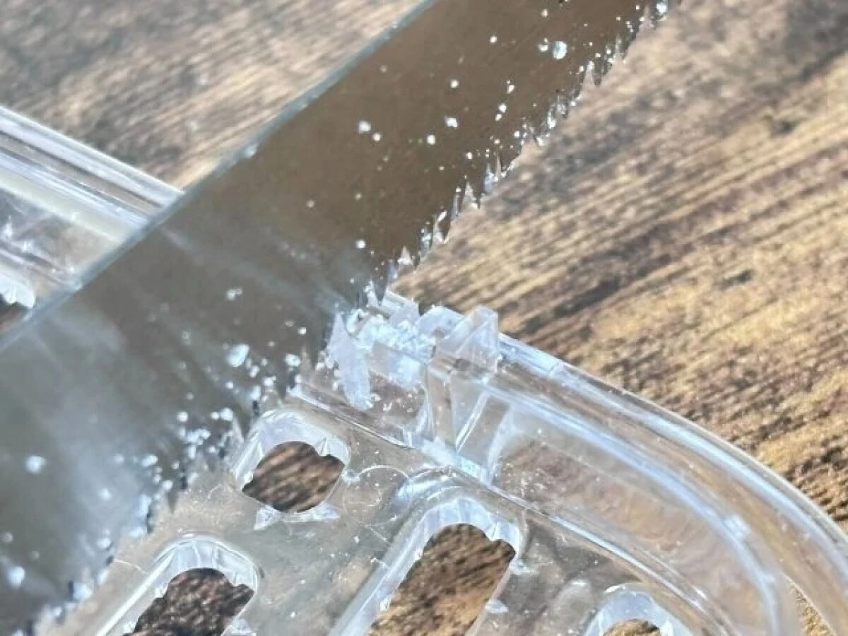 ダイソーののこぎりで透明なプラスチックをカットしている様子