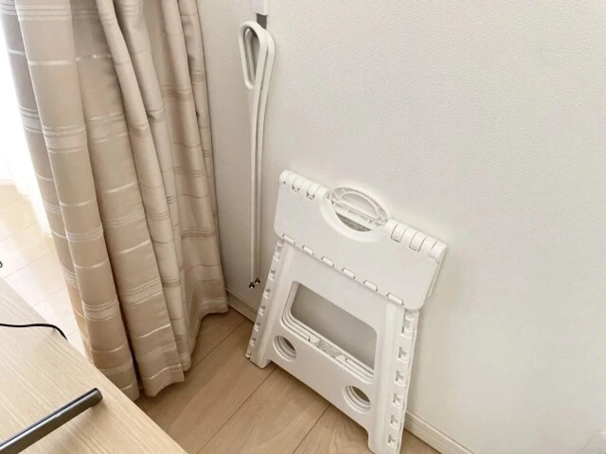 テレビボードの背面に折り畳み式のステップ台と掃除用具を立てかけている様子 テレビボードの背面に折り畳み式のステップ台と掃除用具を立てかけている様子