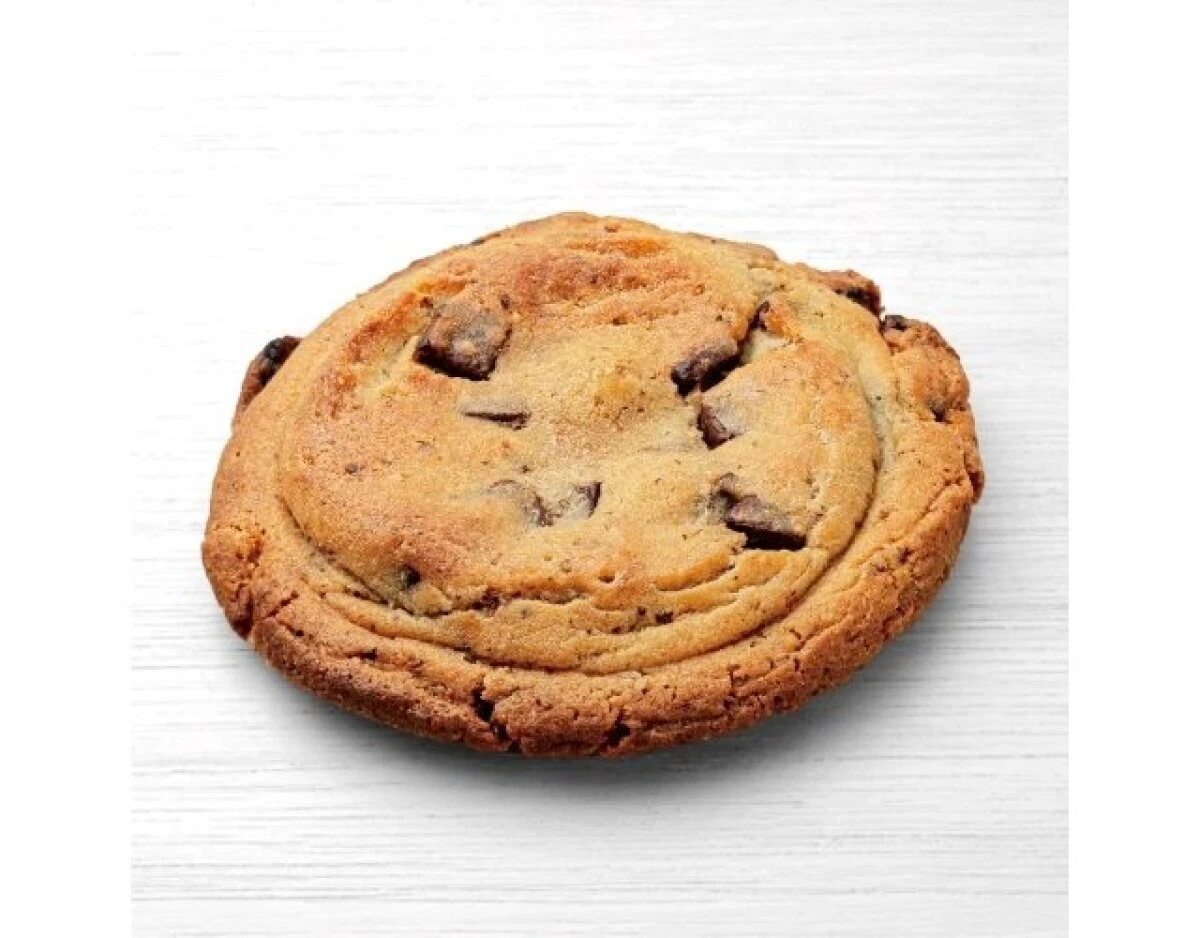 白い木目調の台に置かれた、チョコチップがたくさん入った丸いクッキー