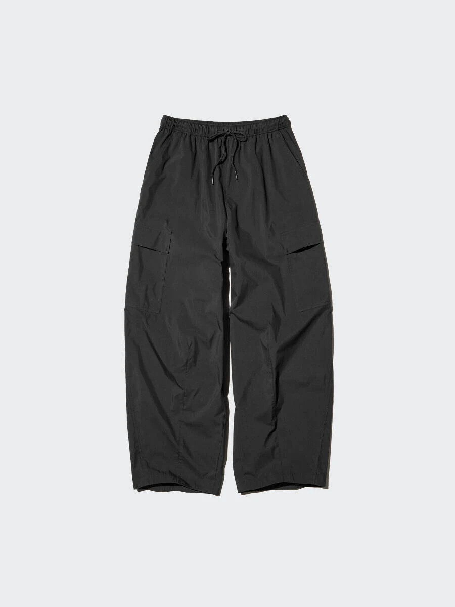 黒色のユーティリティボリュームパンツ。ウエスト紐とフラップポケット。 黒色のユーティリティボリュームパンツ。ウエスト紐とフラップポケット。